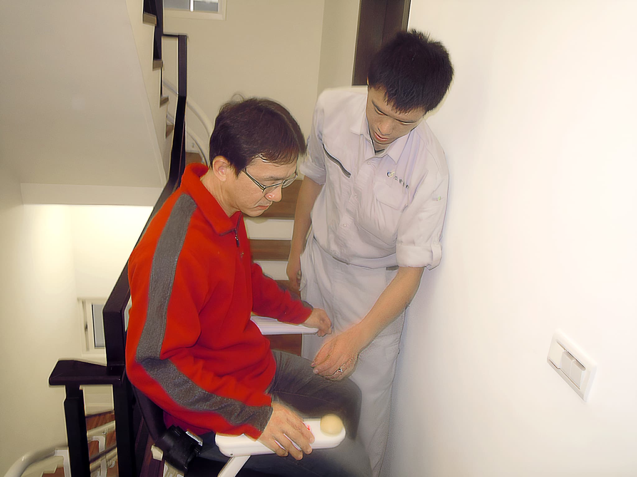 泓電樓梯升降椅的工程師正在教導趙先生如何使用升降椅