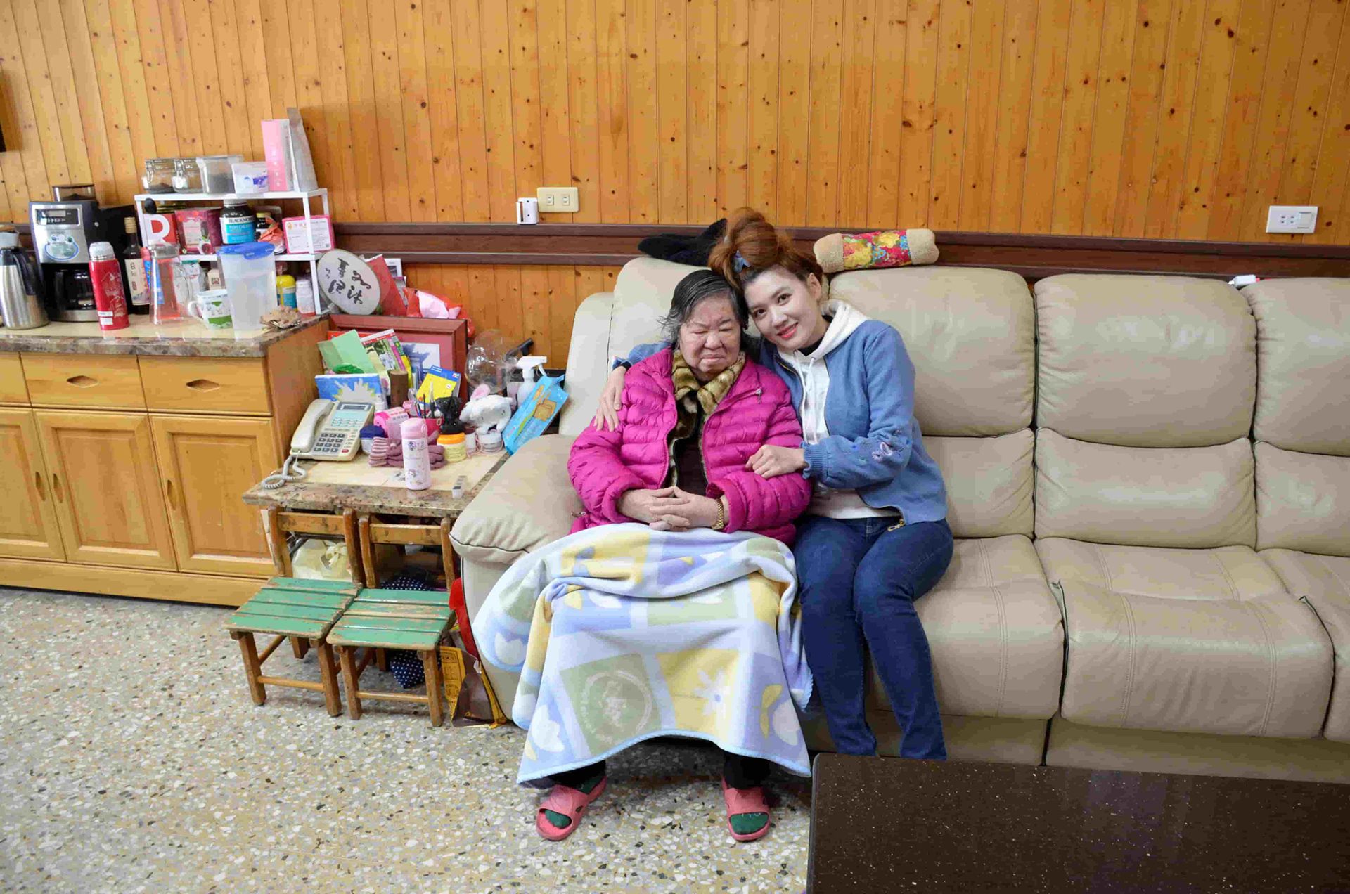 泓電樓梯升降椅的顧客奶奶與孫女坐在沙發上合照留念